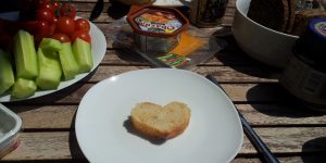 Foto eines gedeckten Tischs. Auf dem Teller im Vordergrund liegt eine Scheibe Brot in Form eines Herzens, ein Brotherz | © Claus R. Kullak | Foto: Lina Dobrowitz | crk-res.de